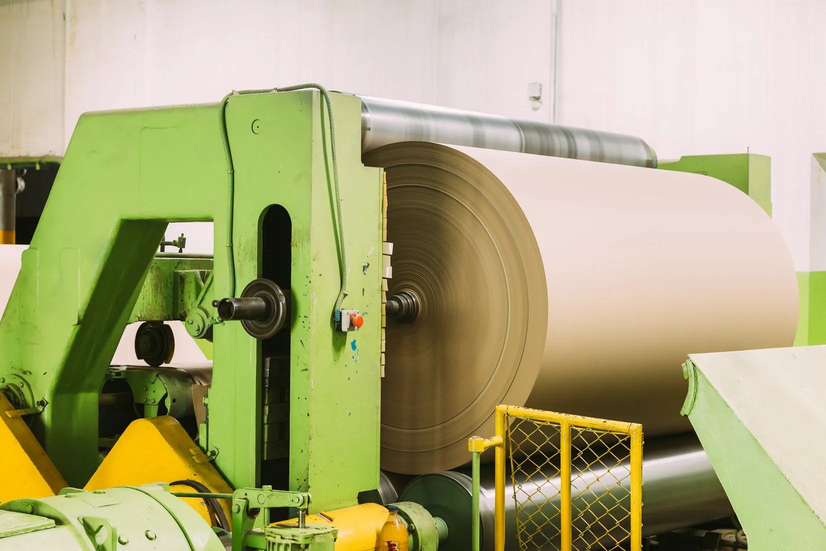 Bobina de papel de gran formato instalada en una máquina industrial utilizada para el procesamiento y conversión de papel.